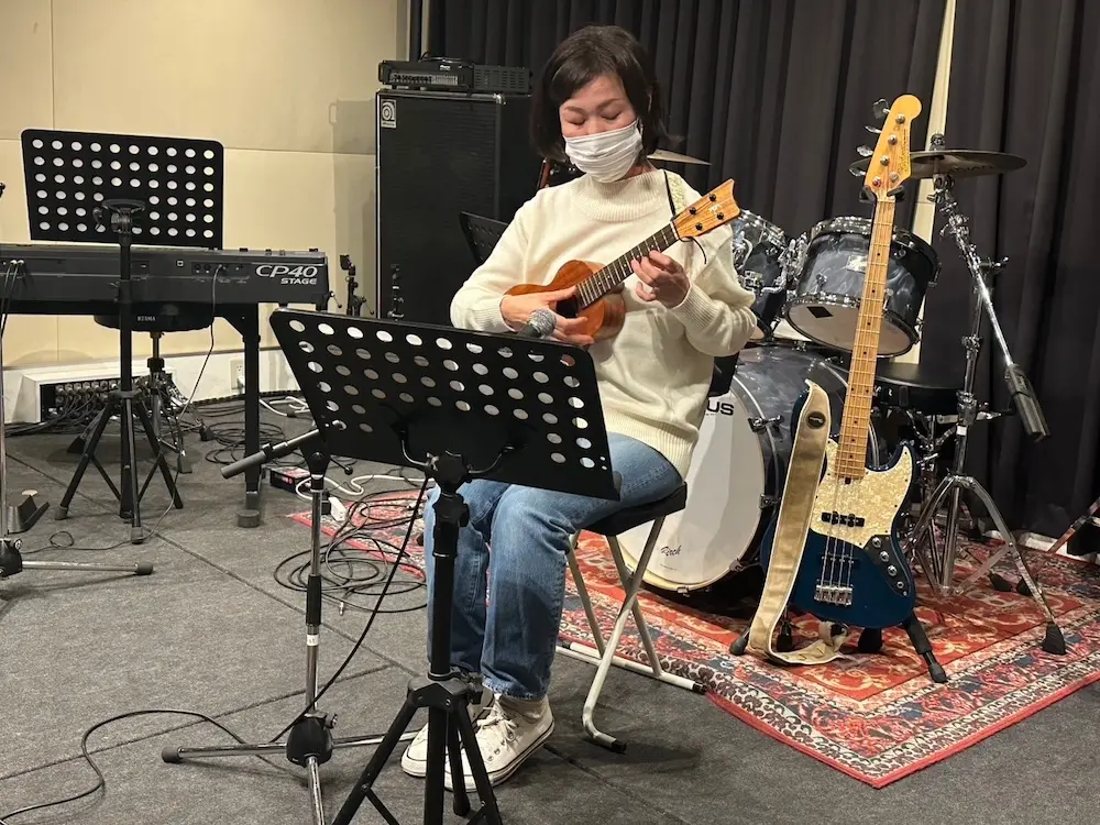 自由が丘のウクレレ教室の発表会で、ステージに座りソロウクレレ（伴奏なしの演奏）を真剣に奏でる生徒さん